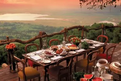 A breakfast table laid on a terrace above the Ngorongoro crater rim at sunrise