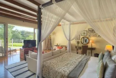 Four-poster bed draped in mosquito netting in a suite at Hemingways Nairobi