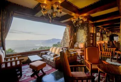 A lodge lounge with chandeliers and picture windows facing the crater