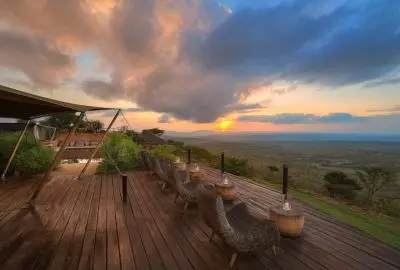 Sundowners set out on the camp deck as the sun sets over Loisaba Conservancy