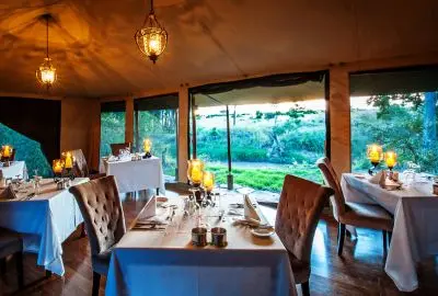 Tables dressed in blue linen in the dining tent at Sand River Masai Mara