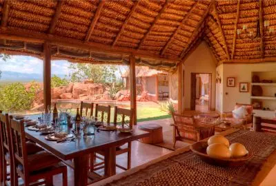 Dining table under a thatched roof looking out across Meru National Park