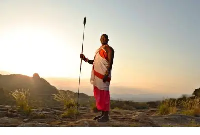 Samburu warrior standing on a hilltop against a golden sunset