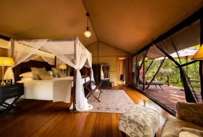Canopied bed and timber floors in a tented suite at Sand River Masai Mara