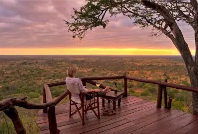 Guests watching the sun set over Meru from the timber deck at Elsa’s Kopje
