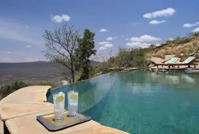 Two chilled drinks on the deck of a lodge infinity pool