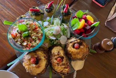 Bush breakfast of salads, fruit and pastries laid out on a wooden table