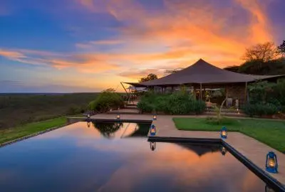 Loisaba Tented Camp mirrored in the still infinity pool at sunset