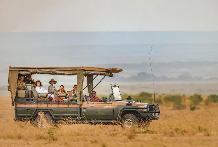 Guests scanning the plains from an open-sided safari vehicle in Amboseli