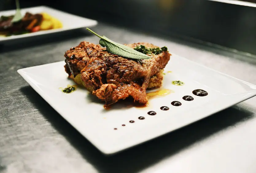 Plated main course garnished with sage at Soroi Luxury Migration Camp