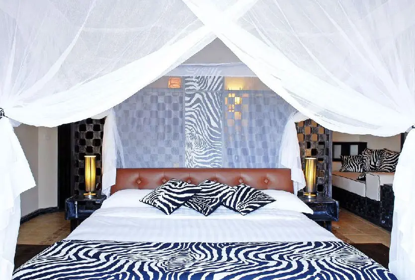 Four-poster bed under a mosquito net in a zebra-print suite at Soroi Blue