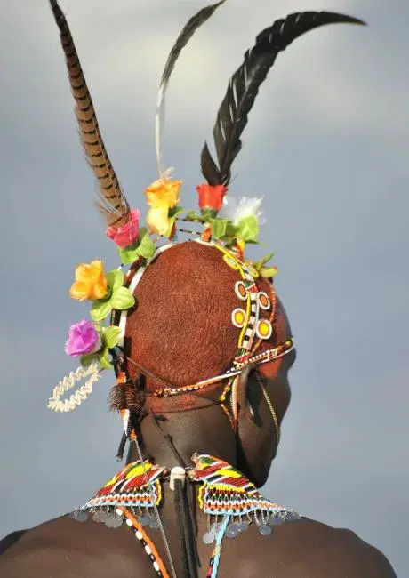 A Samburu moran in a beaded headdress crowned with ostrich feathers and flowers