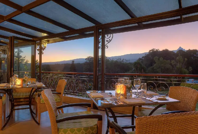 Candlelit tables on a glass-roofed dining terrace looking out to the mountains