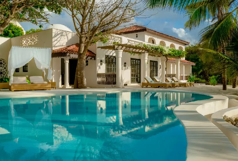 Swahili-style villa wing reflected in the turquoise resort pool