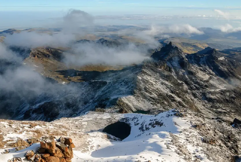 Cloud drifting over rugged mountain peaks seen from the air